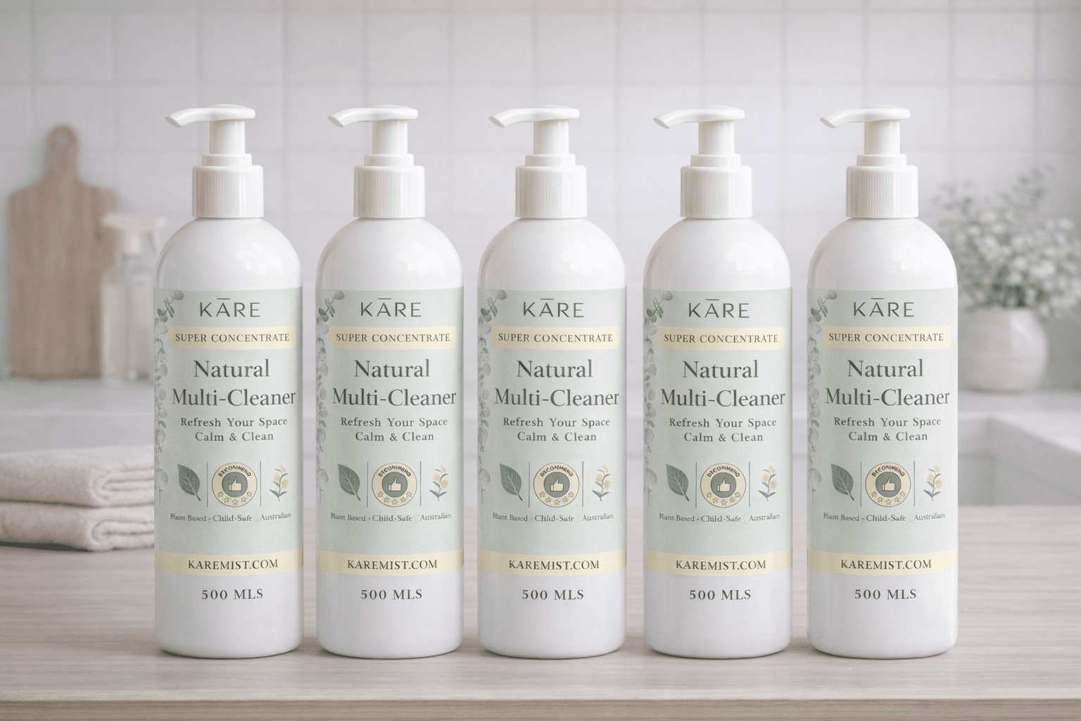 Five white pump bottles of KARE Natural Multi-Cleaner lined up on a wooden counter.