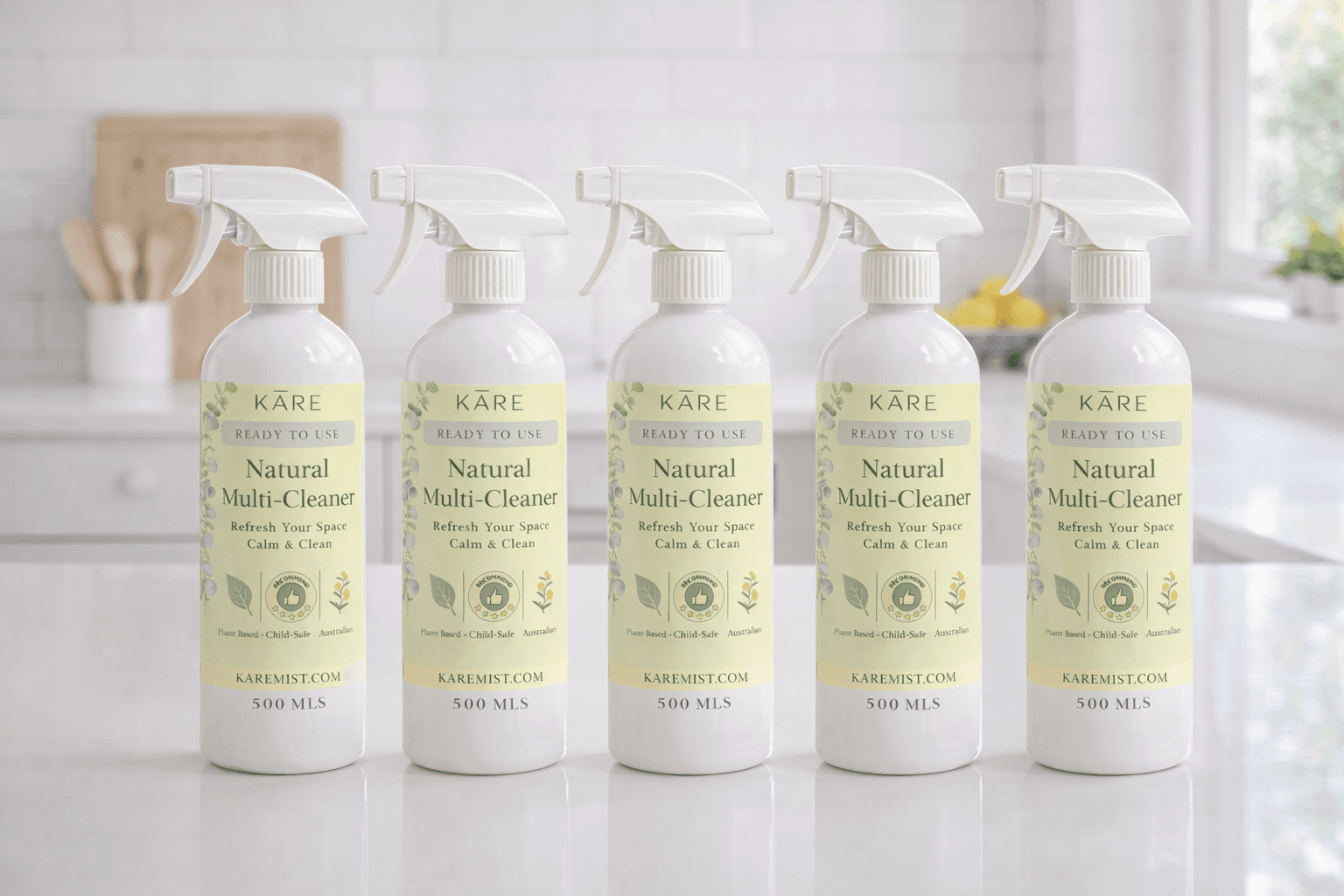 Five white spray bottles of KARE Natural Multi-Cleaner arranged on a clean kitchen counter.